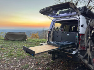 Sunrise with tent and Land Rover on edge of mountain